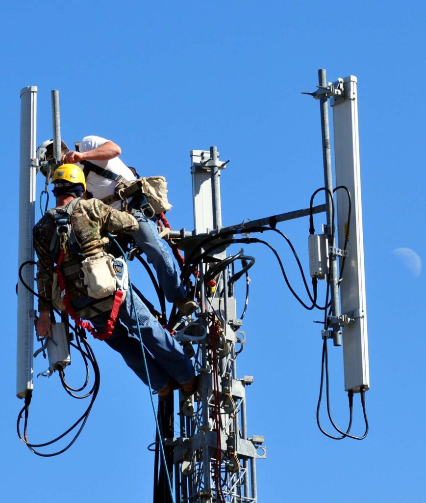 Workers maintaining a telecommunications tower used for mobile networks